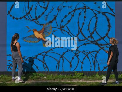 GDANSK, POLOGNE. 05 septembre 2022. Deux jeunes femmes regardent une fresque pro-ukrainienne créée par l'artiste polonais Dawid Janiak. Près de 30 peintures murales anti-guerre ont été peintes sur le mur à l'arrêt PKM Gdansk Jasien Mapka dans le cadre du projet "en solidarité avec l'Ukraine" lancé par le PKM et l'Académie des beaux-arts de Gdansk. Beaucoup de ces peintures murales sont liées au conflit russo-ukrainien de 2022. Crédit : ASWphoto/Alamy Live News Banque D'Images