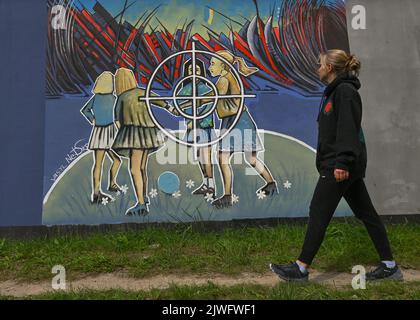 GDANSK, POLOGNE. 05 septembre 2022. Une jeune femme marche à côté d'une fresque pro-ukrainienne et anti-guerre créée par l'artiste Vasyl Netsko. Près de 30 peintures murales anti-guerre ont été peintes sur le mur à l'arrêt PKM Gdansk Jasien Mapka dans le cadre du projet "en solidarité avec l'Ukraine" lancé par le PKM et l'Académie des beaux-arts de Gdansk. Beaucoup de ces peintures murales sont liées au conflit russo-ukrainien de 2022. Crédit : ASWphoto/Alamy Live News Banque D'Images