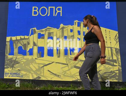 GDANSK, POLOGNE. 05 septembre 2022. Une jeune femme marche à côté d'une fresque pro-ukrainienne et anti-guerre créée par l'artiste polonaise Julia Kochanska. Près de 30 peintures murales anti-guerre ont été peintes sur le mur à l'arrêt PKM Gdansk Jasien Mapka dans le cadre du projet "en solidarité avec l'Ukraine" lancé par le PKM et l'Académie des beaux-arts de Gdansk. Beaucoup de ces peintures murales sont liées au conflit russo-ukrainien de 2022. Crédit : ASWphoto/Alamy Live News Banque D'Images