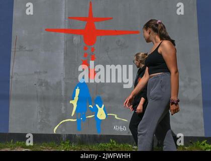 GDANSK, POLOGNE. 05 septembre 2022. Deux jeunes femmes marchent à côté d'une fresque pro-ukrainienne et anti-guerre. Près de 30 peintures murales anti-guerre ont été peintes sur le mur à l'arrêt PKM Gdansk Jasien Mapka dans le cadre du projet "en solidarité avec l'Ukraine" lancé par le PKM et l'Académie des beaux-arts de Gdansk. Beaucoup de ces peintures murales sont liées au conflit russo-ukrainien de 2022. Crédit : ASWphoto/Alamy Live News Banque D'Images