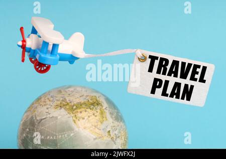 Concept de voyage et d'affaires. Sur fond bleu, un globe et un avion avec un panneau - PLAN DE VOYAGE. Globe hors foyer. Banque D'Images