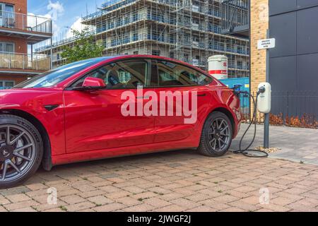 Une voiture rouge Tesla charge sa batterie à un point de charge de véhicule électrique à Southampton, Angleterre, Royaume-Uni Banque D'Images