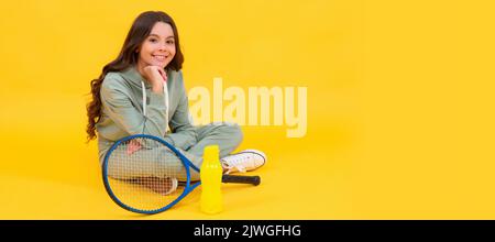 un enfant joyeux s'assoit dans des vêtements de sport avec raquette de badminton et bouteille d'eau sur fond jaune, détendez-vous. Affiche horizontale de visage d'enfant isolé, bannière Banque D'Images