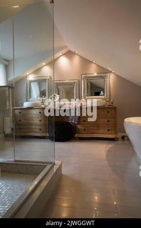 Salle de bains principale avec armoires en bois et miroirs encadrés d'argent à l'intérieur d'une luxueuse maison. Banque D'Images