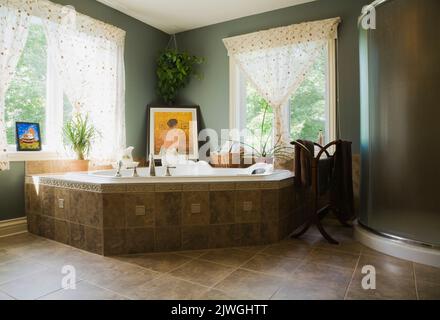 Salle de bains principale avec baignoire à remous et cabine de douche en verre à l'intérieur d'une maison de style cottage. Banque D'Images