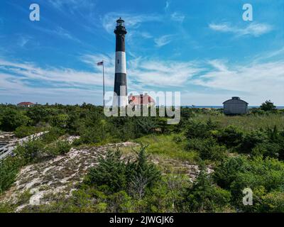 Vue sur le phare de Fire Island prise du côté de Great South Bay avec le musée et un drapeau américain soufflant dans le vent. Banque D'Images