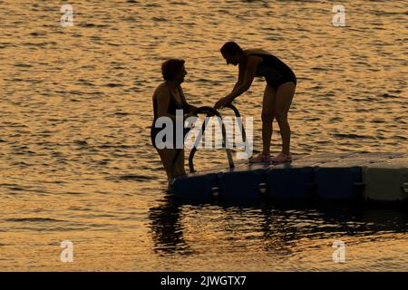 Deux femmes nageant au coucher du soleil à la mer Égée. Banque D'Images