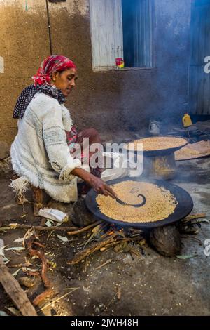 LALIBELA, ETHIOPIE - 29 MARS 2019: Une femme locale torréfaction des grains de teff pour le pain injera, Ethiopie Banque D'Images