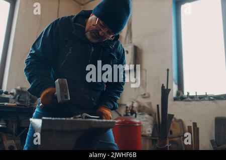 Forge forge et fait des détails en métal avec un marteau et une enclume à la forge. Banque D'Images