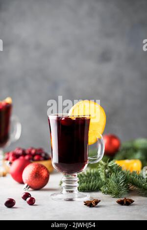 Verre de vin chaud entouré d'épices, de fleurs d'orange et de branches d'un arbre de Noël. Banque D'Images