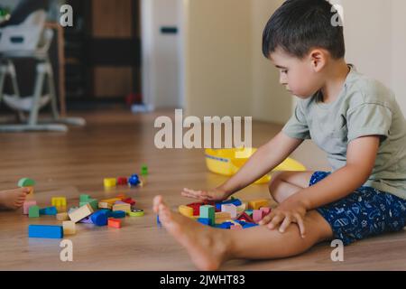 Garçon assis sur le sol et construisant un jouet de pyramide. Développement des jeunes enfants. Bonne famille.développement des enfants, jeux éducatifs Banque D'Images