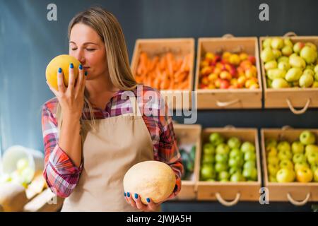 Femme travaille dans la boutique de fruits et légumes. Elle examine les marchandises. Banque D'Images