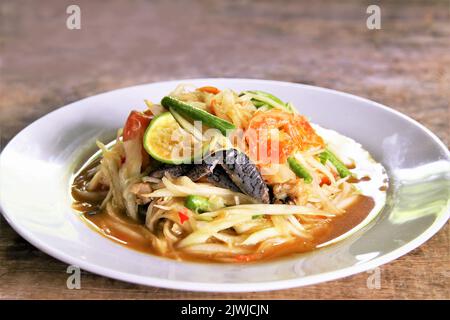 Célèbre salade de papaye thaï avec crevettes séchées et crabe salé sur plaque blanche photo sur fond de bois Banque D'Images