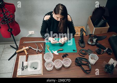 Tanner femme faisant des marchandises de ceinture de harnais en cuir sur l'atelier.Processus de travail de l'artisan du cuir. Banque D'Images