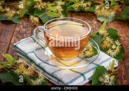 linden fleurs sur un bois et un verre transparent tasse de thé parfumé. concept de médecine de guérison à la maison Banque D'Images