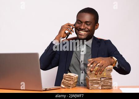 un homme d'affaires africain excité avec beaucoup d'argent faisant un appel téléphonique Banque D'Images