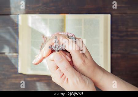 Mains pliées dans la prière avec rosaire croisé sur un fond de la Sainte Bible.concept de foi, de spiritualité et de religion Banque D'Images