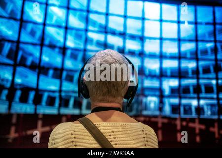 Femme âgée avec casque devant la projection d'écran multimédia. Mise au point peu profonde sur l'arrière-plan Banque D'Images