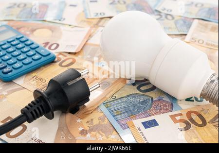 Prix de l'énergie coût sur le concept de l'Europe. Ampoule, fiche électrique, billets en euros et calculatrice encore vie Banque D'Images