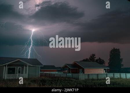 Thunderbolt sur la maison dans le village et sombre ciel orageux sur le fond. Banque D'Images