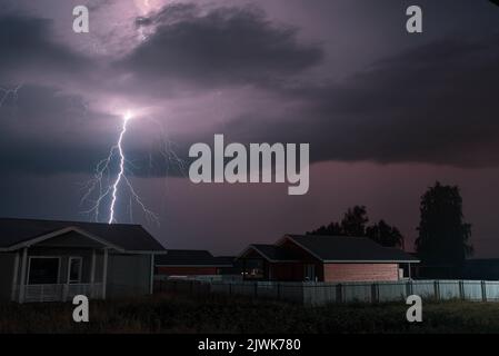 Thunderbolt sur la maison dans le village et sombre ciel orageux sur le fond. Banque D'Images