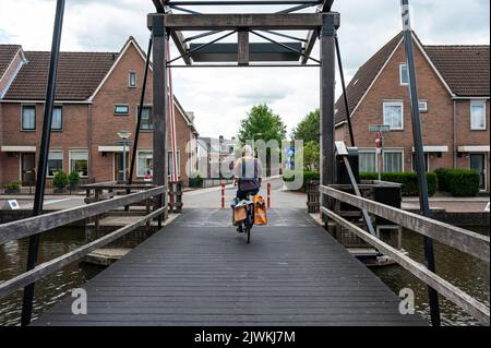 Meppel, Overijssel, pays-Bas, 07 20 2022 - un liveur de poste conduit son vélo sur un vieux pont Banque D'Images