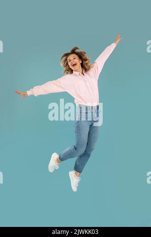 Photo verticale de la femme posant en milieu d'air, fond bleu Banque D'Images
