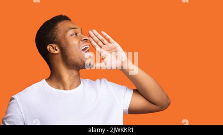 Profil Portrait de l'Africain criant Guy posant sur fond Orange Banque D'Images