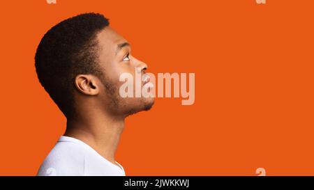 Vue latérale de Serious Black Guy posant sur un fond orange Banque D'Images