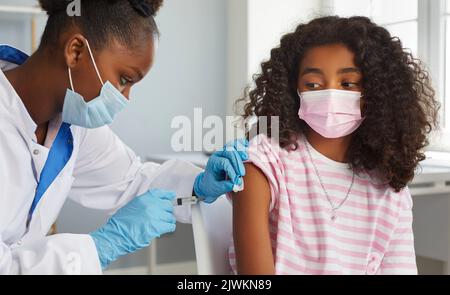 Une adolescente afro-américaine courageuse reçoit une dose de rappel du vaccin contre le coronavirus. Banque D'Images