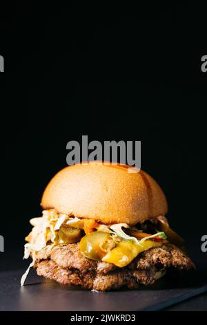 Bouchez le cheeseburger avec les légumes et le jalapeños sur une assiette blanche Banque D'Images