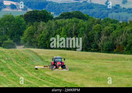 Red Massey Ferguson 7719 S Tractor & Claas Disco 3200c foin marécageuses - pâturage sur les terres agricoles à flanc de colline, campagne pittoresque de Wharfedale, Yorkshire, Angleterre, Royaume-Uni. Banque D'Images