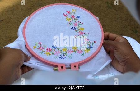 Sur l'épaule vue d'une femme asiatique créant une main broderie Lazy Daisy Stitch sur un tissu.sur ce tissu blanc petites fleurs avec des feuilles sont craf Banque D'Images