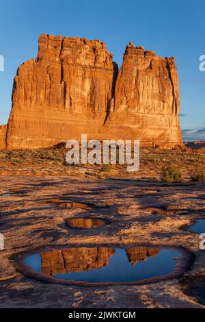 L'orgue, un monolithe de grès dans les tours du palais de justice, se reflète dans un pothole d'eau de pluie dans le parc national d'Arches, Moab, Utah. Banque D'Images