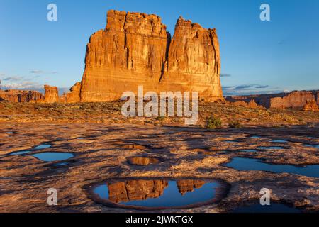 L'orgue, un monolithe de grès dans les tours du palais de justice, se reflète dans un pothole d'eau de pluie dans le parc national d'Arches, Moab, Utah. Banque D'Images