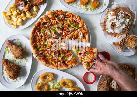 Homme mains tenant la tranche de pizza du doner sur la table du restaurant vue du dessus plan Banque D'Images