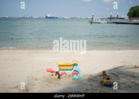 jouets en plastique multicolores sur une grande plage de sable Banque D'Images