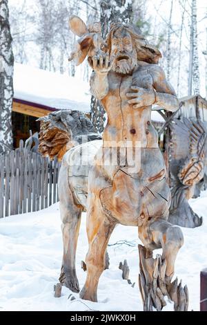 Figurine en bois traditionnelle sibérienne. Ancienne sculpture en bois dans la forêt, Centaur tenant une fée forestière dans sa main. Sibérie, périphérie du parc. Sculpté Banque D'Images