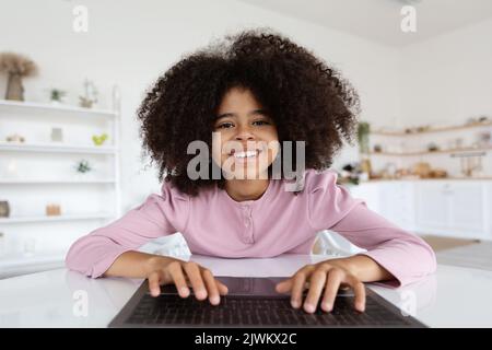 Gros plan de la jeune fille noire gaie qui tape sur le clavier de l'ordinateur portable Banque D'Images