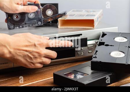 La main femelle insère une cassette VHS dans le magnétoscope pour regarder la vidéo. La main femelle tient une cassette audio magnétique pour la musique. vint rétro Banque D'Images