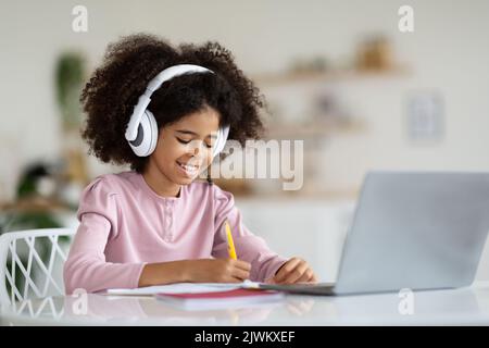 Joyeux élève afro-américain assis devant un ordinateur portable Banque D'Images