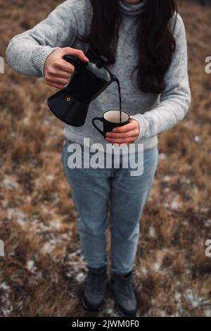 Gros plan d'une femme qui verse du café de la marmite Moka dans une tasse à l'extérieur Banque D'Images