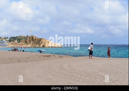 Couple habillé regardant l'île de Blanes depuis la plage. Banque D'Images