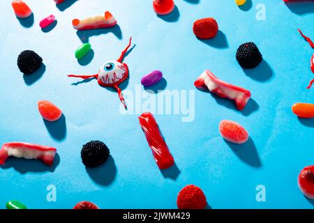 Plusieurs jouets effrayants pour les yeux et bonbons d'halloween sur une surface bleue Banque D'Images