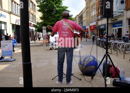 Un chrétien du Sud indien chantant et jouant de la guitare dans le centre commercial Broadmead de Bristol, au Royaume-Uni, portant un t-shirt « Keep calm and trust in god » Banque D'Images
