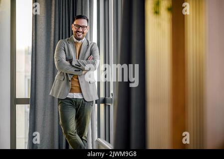 Photo d'un jeune homme d'affaires heureux, debout et armé dans le hall de l'entreprise. Banque D'Images