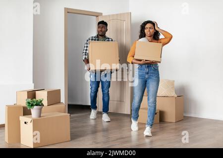 Un couple noir dégoûté entre dans une nouvelle Bad House transportant des boîtes mobiles Banque D'Images