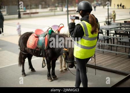 Une fille conduit des enfants à cheval dans la rue. Banque D'Images