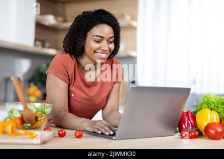 Bonne jeune femme africaine américaine blogger dactylographiant sur ordinateur portable, ont chat en ligne Banque D'Images