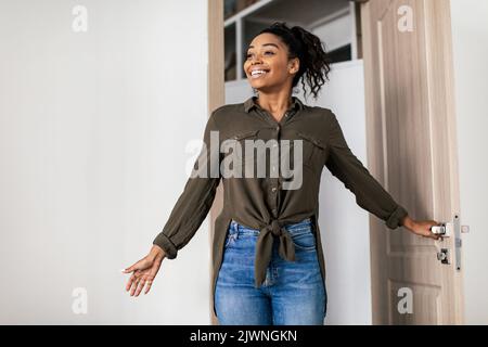 Une dame afro-américaine excitée qui entre chez elle debout à la porte ouverte Banque D'Images